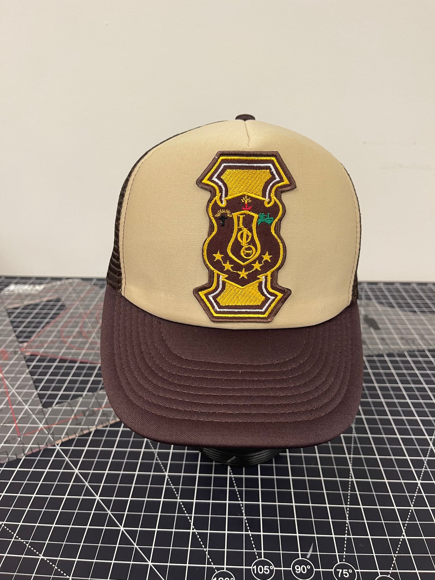 Iota Shield Emblem Trucker Hat – Tan/Brown Edition